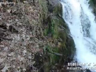 Asiatiskapojke tvilling suger axel av waterfall
